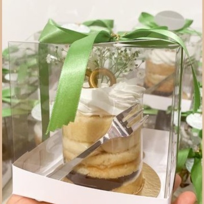 Bolo decorado em caixa transparente com fita verde e garfo dentro
