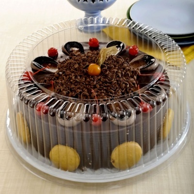 Bolo de chocolate decorado com cerejas e bolachas dentro de tampa plástica transparente