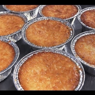 Oito bolos dourados em formas de alumínio sobre superfície escura