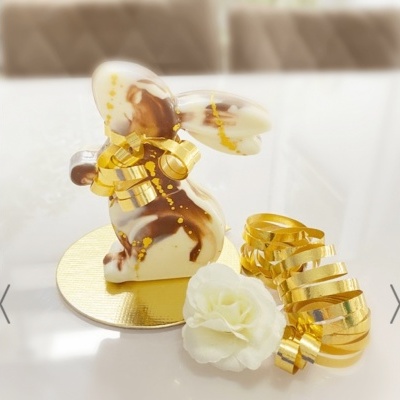 Figura de coelho decorativa em chocolate com detalhes dourados e flor branca