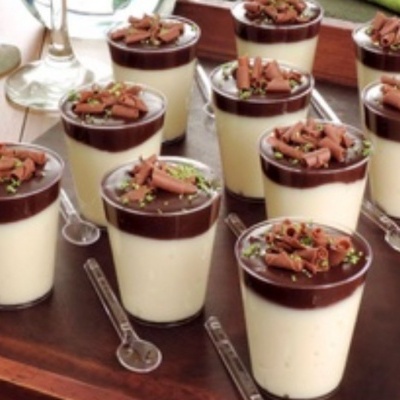 Doze copos de sobremesa com creme branco e cobertura de chocolate com raspas em bandeja de madeira