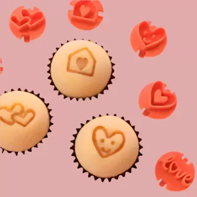 Cupcakes com decoração de corações e carimbos vermelhos sobre fundo rosa