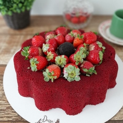 bolo vermelho decorado com morangos e amora sobre base branca com texto