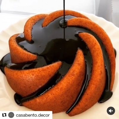 Bolo castanho com cobertura preta a ser derramada num prato branco