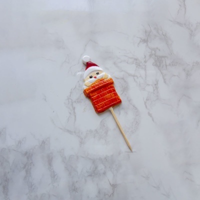 Doce decorativo de Papa Noel em chaminé com palito sobre mármore branco