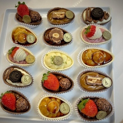 Bombons variados com morango, Oreo, nozes e chantili em forminhas brancas numa bandeja branca