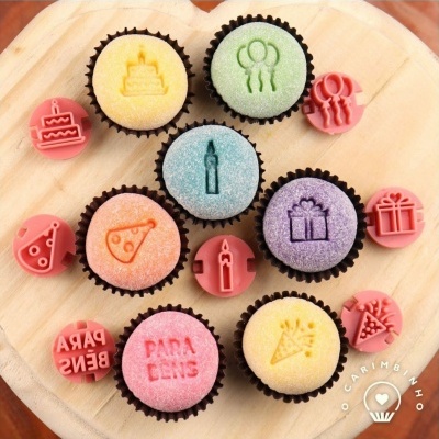 Cupcakes coloridos com desenhos em relevo e carimbos correspondentes sobre tábua de madeira