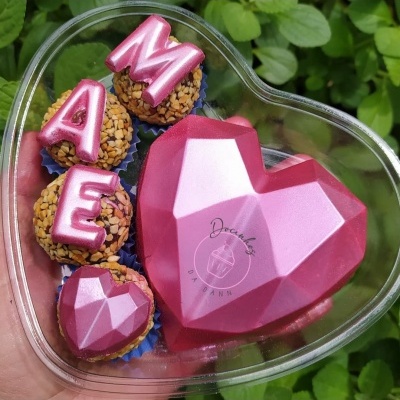 Caixa coração transparente com chocolate rosa facetado e brigadeiros com letras 'MAE'