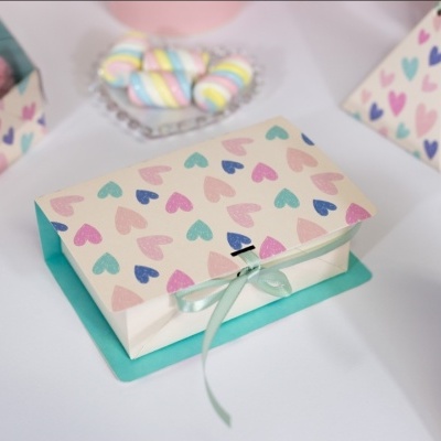Caixa de papel decorativa com corações coloridos e fita verde