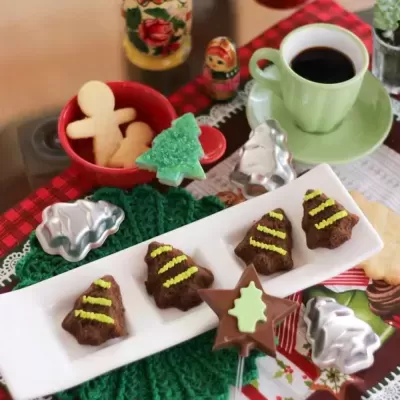 Mesa com bolachas decoradas de Natal, chávena de café verde e formas metálicas para bolachas
