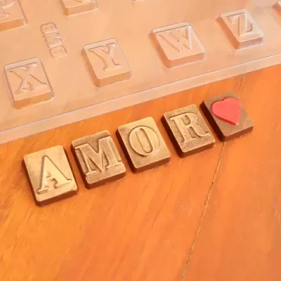 Blocos de madeira formando a palavra AMOR com um coração e molde de silicone ao fundo