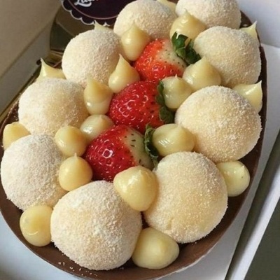 Ovo de chocolate recheado com bolinhas de massa branca, morangos frescos e creme amarelo