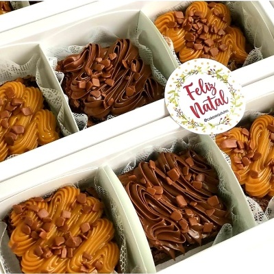 Caixa com pastéis decorados de caramelo e chocolate e etiqueta Feliz Natal