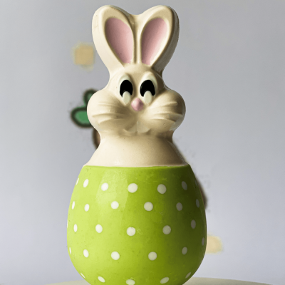 Figura decorativa de coelho verde com bolinhas brancas em fundo cinzento