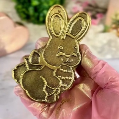 Molde de coelho dourado em mãos com luva rosa