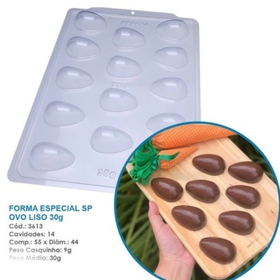 Forma de plástico branca para ovo liso com 14 cavidades e texto técnico em português, com chocolate moldado em tabuleiro de madeira