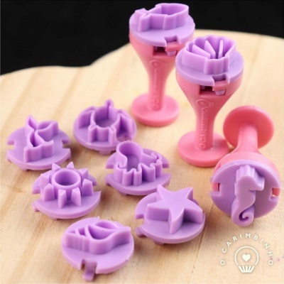 Carimbos de formato marítimo rosa e lilás sobre superfície de madeira