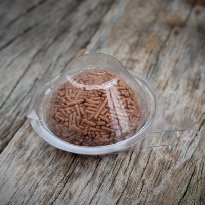 Embalagem plástica transparente com pellets marrons sobre madeira envelhecida