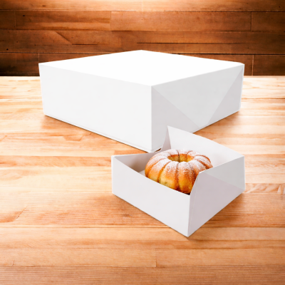 Bolo redondo com açúcar em pó numa caixa branca sobre mesa de madeira