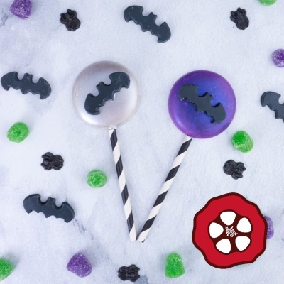 Pirulitos redondos com morcegos pretos e confeitos coloridos sobre fundo branco