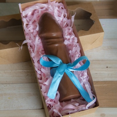 Figura de chocolate castanho com laço azul dentro de caixa de cartão com enchimento cor-de-rosa