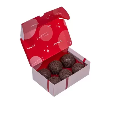 Caixa de bolas de chocolate, interior vermelho com padrões brancos.