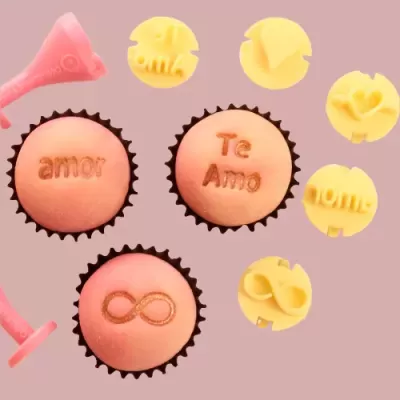 Cupcakes cor-de-rosa com palavras e símbolos gravados, rodeados por carimbos amarelos em fundo rosa.