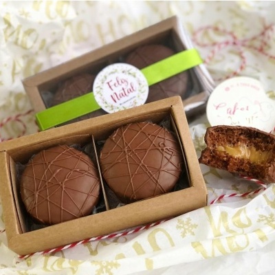Caixas com chocolates redondos mostrando texturas e recheio cremoso em papel de embrulho decorativo