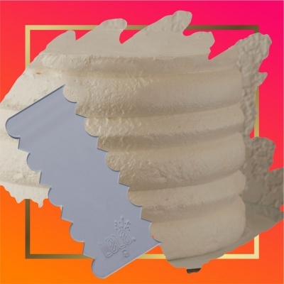 Espátula cinza com bordas onduladas sobre pasta branca texturizada em fundo degradê vermelho e laranja