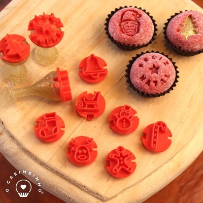 Carimbos vermelhos natalícios e cupcakes decorados com açúcar cor-de-rosa sobre tábua de madeira