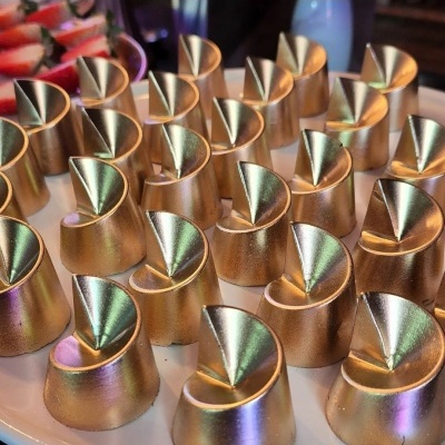 Pequenos bolos dourados com design em espiral numa bandeja branca