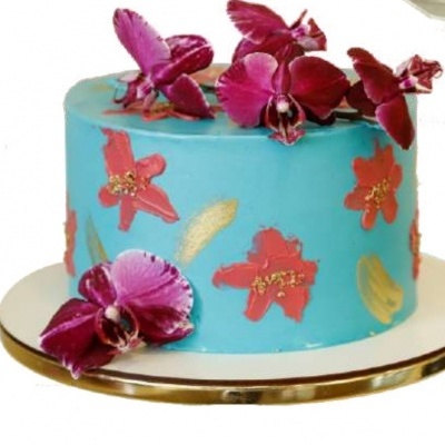 Bolo azul decorado com flores vermelhas e douradas e flores naturais roxas