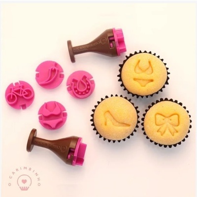 Carimbos para cupcakes com formas decorativas em silicone cor de rosa e marrom, e cupcakes com desenhos estampados.