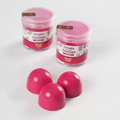 Bombons rosa brilhantes e frascos de corante em gel para chocolate