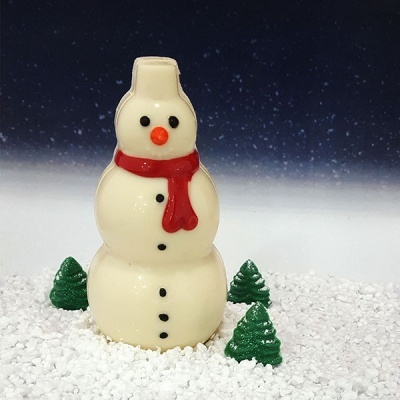 Boneco de neve de chocolate branco com cachecol vermelho e árvores verdes na neve