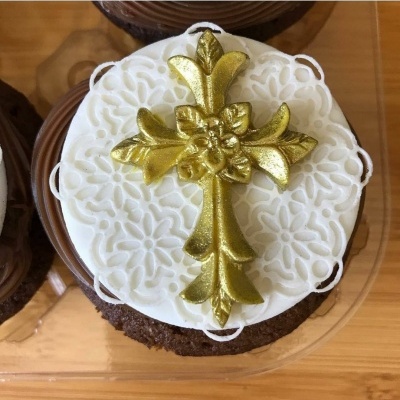 Bolo de chocolate com cobertura branca e cruz dourada decorativa