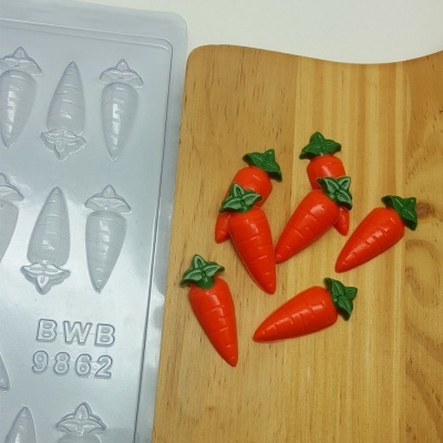 Formas de cenouras em plástico e cinco cenouras laranja com folhas verdes sobre madeira