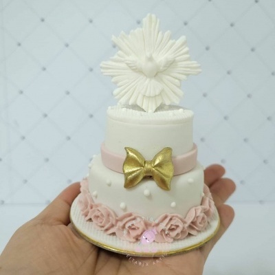 Mini bolo branco e rosa com decoração de flores, laço dourado e pomba no topo.