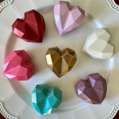 Sete corações de chocolate coloridos facetados num prato branco