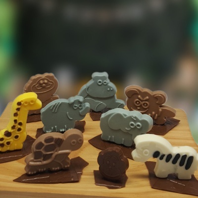 Figuras de animais de chocolate em várias cores sobre base de madeira clara