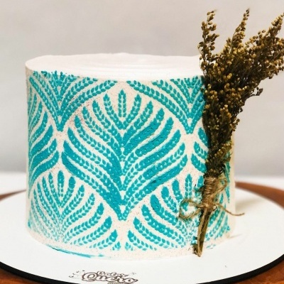 Bolo decorado com padrão turquesa e ramo seco amarrado