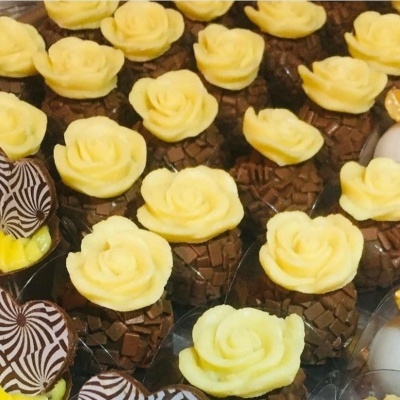 Doces variados com flores amarelas, chocolate e nozes em bandeja