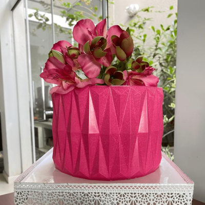 Vaso decorativo rosa com flores artificiais e textura geométrica em ambiente interior