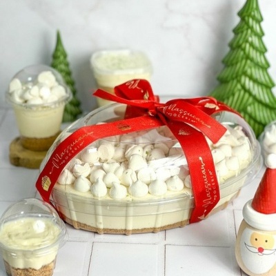 Tarte oval decorada com nuvens brancas e fita vermelha com texto, copos de sobremesas e decoração natalícia