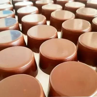 Bombons de chocolate castanho brilhantes alinhados em linhas sobre fundo branco