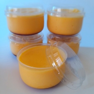 Recipientes de plástico com creme amarelo alaranjado e tampas transparentes