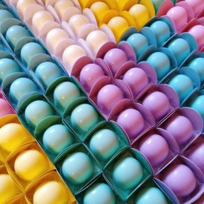 Ovos coloridos organizados em embalagens plásticas alinhadas por cor