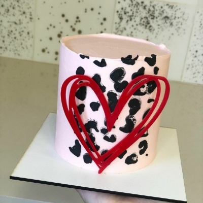 Bolo branco com manchas pretas e coração vermelho