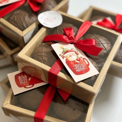 Caixas com chocolates, fitas vermelhas, etiquetas com Pai Natal e texto Feliz Natal