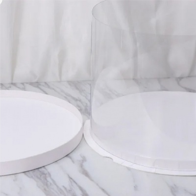 Bolo branco redondo com cobertura transparente numa base branca sobre superfície mármore